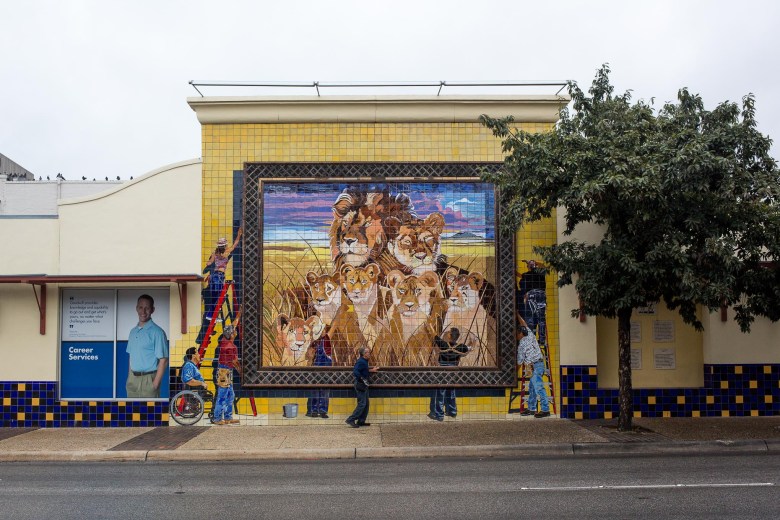 Artist Jesse Treviño runs his hand along the framing border of his mural Chapa Lion which was installed in 2003.