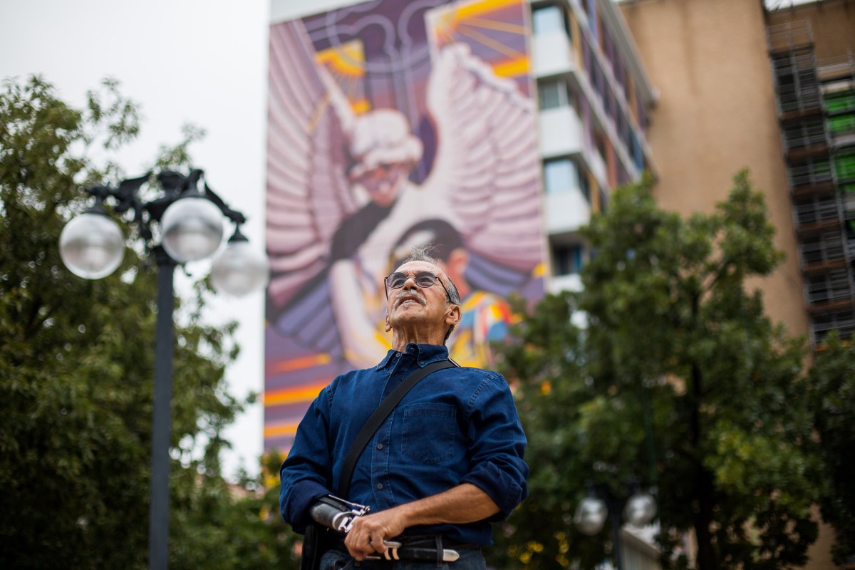 Artist Jesse Treviño stands in front of his nine-story mural titled Spirit of Healing in 2016. Treviño passed away on Monday at the age of 76.