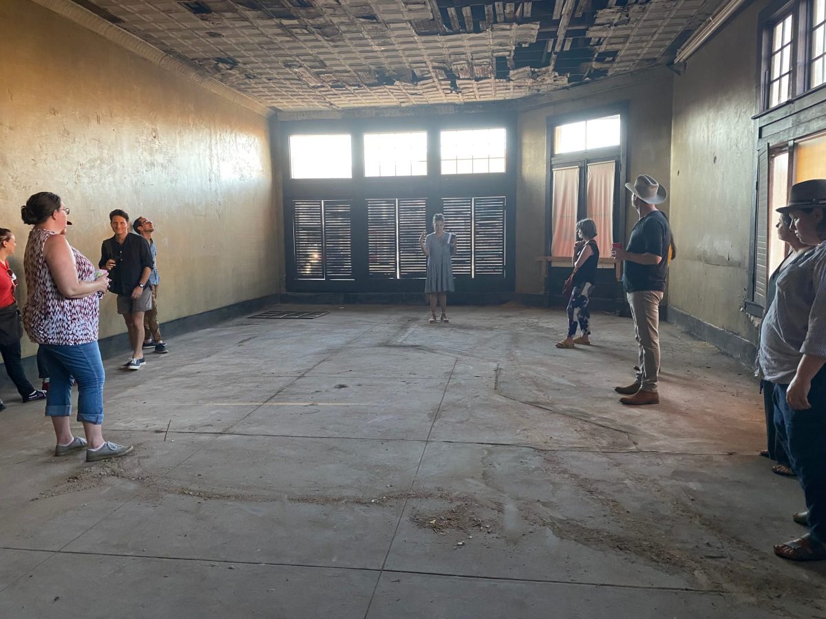 Curator Leslie Moody Castro demonstrates that the Williamson and Bell County Line runs through a former tavern in downtown Bartlett, marked by inset floor tile.