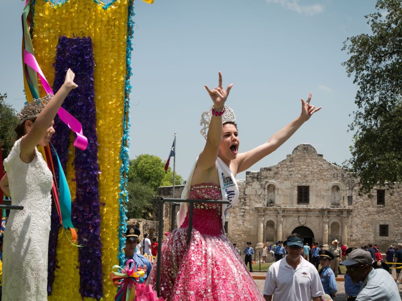 Miss Fiesta San Antonio holds up her hands in a "rock on" gesture at the Battle of Flowers Parade.