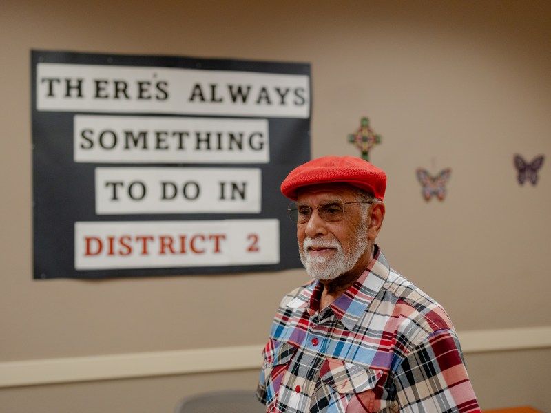 Eugene Hines, member of the District 2 Senior Center, stands in front of a sign that reads "there's always something to do in District 2".