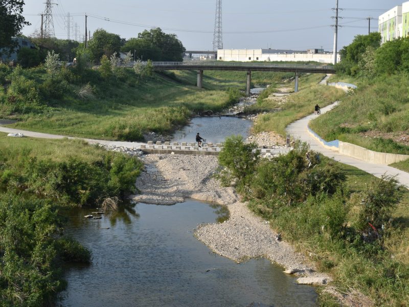 A cyclist rides over Alazan Creek at the intersection of the Apache Creek and Alazan Creek greenways.