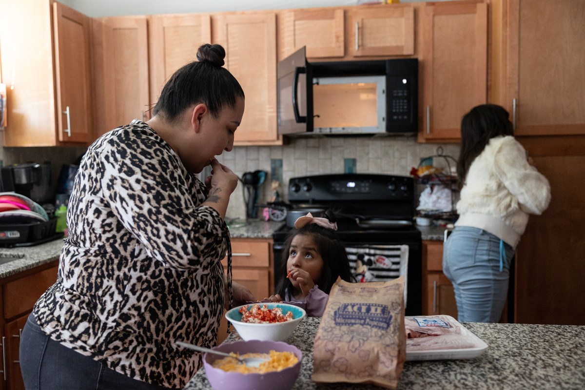 Lisette Medina prepares a popcorn snack for her daughter Estephanie Ochoa, 5, Monday at their home. A packet of pork chops that her sister bought for her family thaws on the countertop, which Medina will prepare for dinner later.