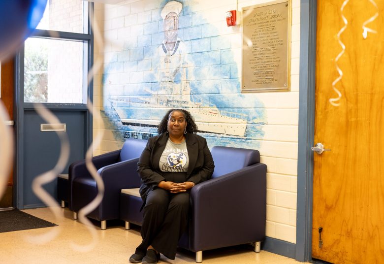 Tondra Williams poses for a portrait in front of one of the murals painted by Curtis Braziel inside of Dorie Miller Elementary School.