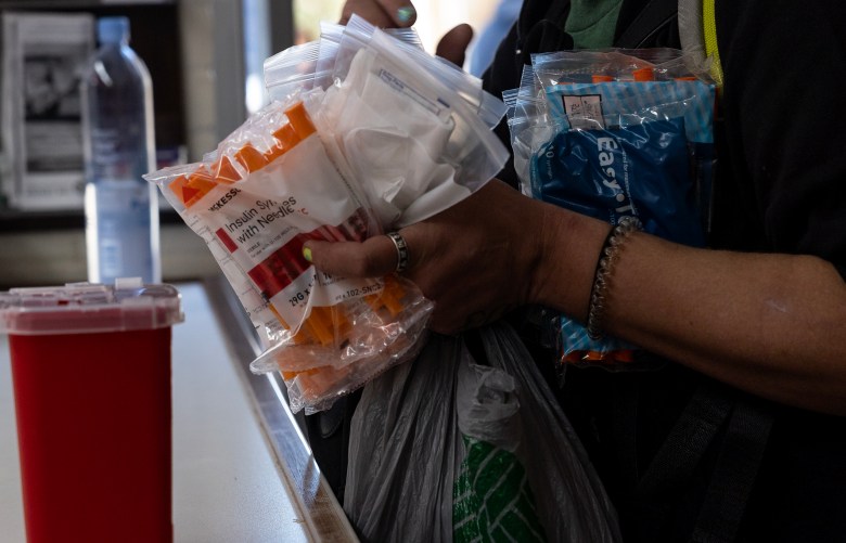 A homeless woman picks up clean needles and a clean sharps container from the harm reduction office at Corazón Ministries on Monday.  Clean needle exchange programs are very rare in the state of Texas.