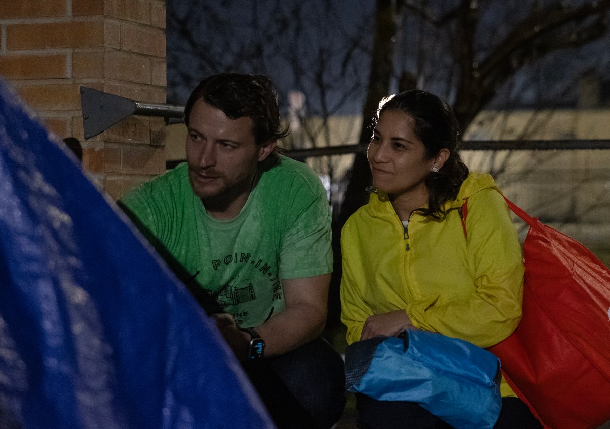 Dan Rossiter (left) and Anissa Mahone speak with a homeless woman in the rain on Brooklyn Avenue late Tuesday during the annual point-in-time count in the downtown area.