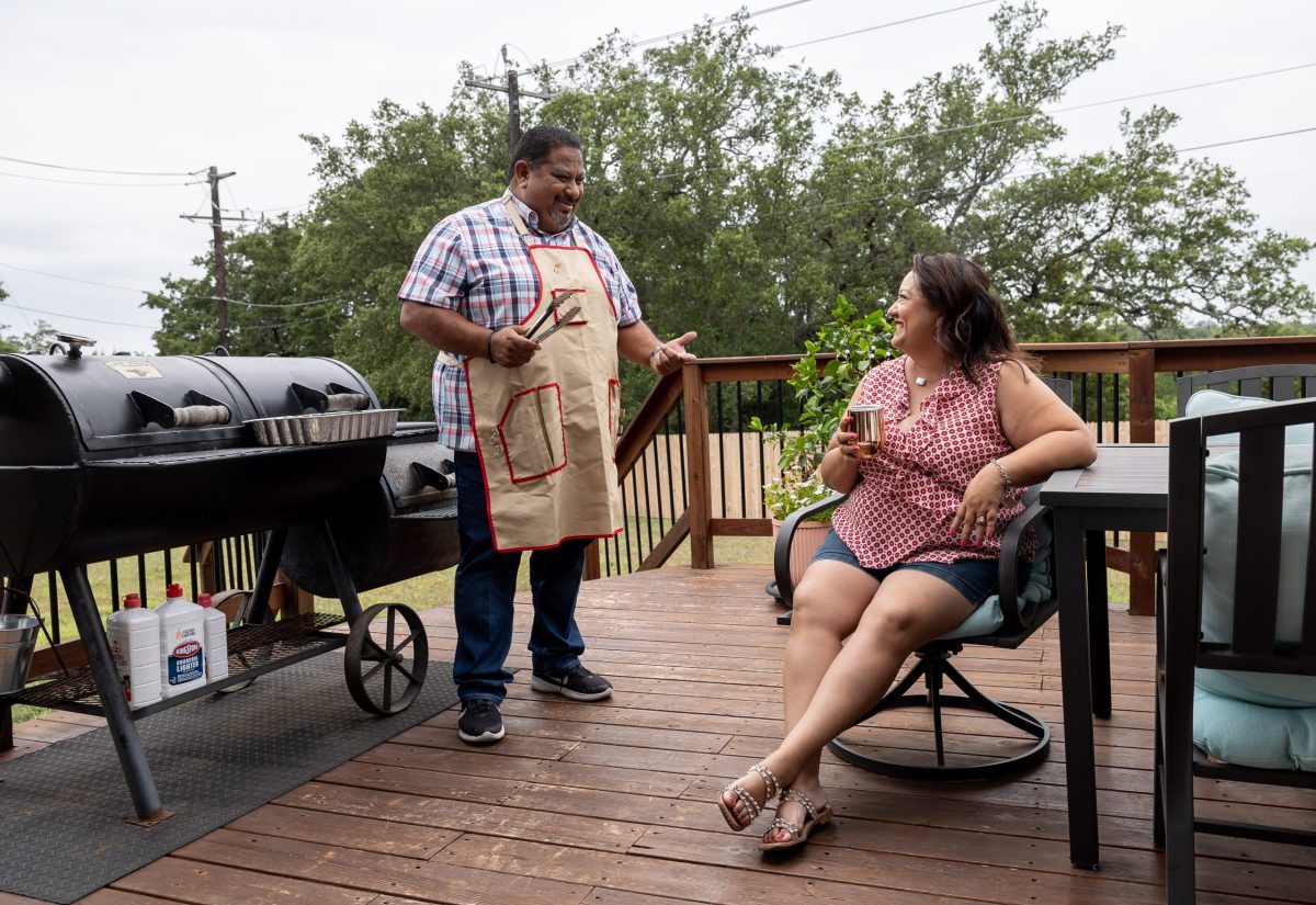 Benjamin Godina and his wife Amanda Godina prepare for a family BBQ at their house in Alamo Ranch Friday.