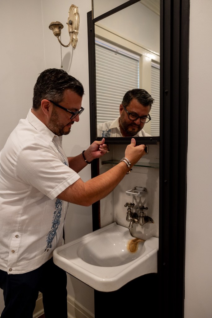 Jacob Valenzuela reveals a small vintage sink and shelf behind a sliding mirror where his great uncle would shave.