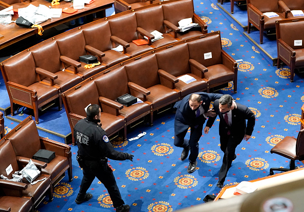 Members of congress run for cover as protesters try to enter the House Chamber during a joint session of Congress on January 6, 2021 in Washington, DC.