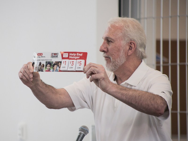 San Antonio Spurs coach Gregg Popovich holds up a San Antonio Food Bank donation strip from H-E-B which encourages shoppers to add donations to their grocery bill.