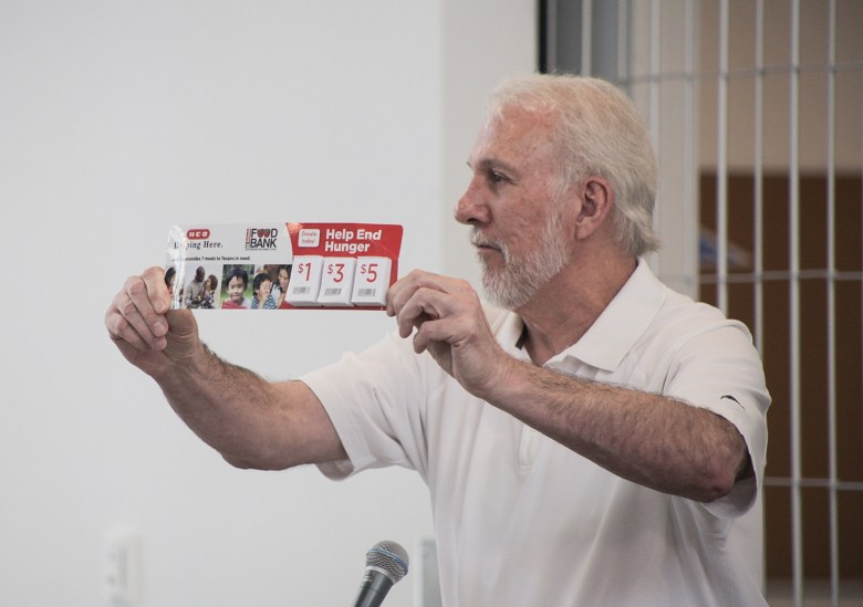 San Antonio Spurs coach Gregg Popovich holds up a San Antonio Food Bank donation strip from H-E-B which encourages shoppers to add donations to their grocery bill.