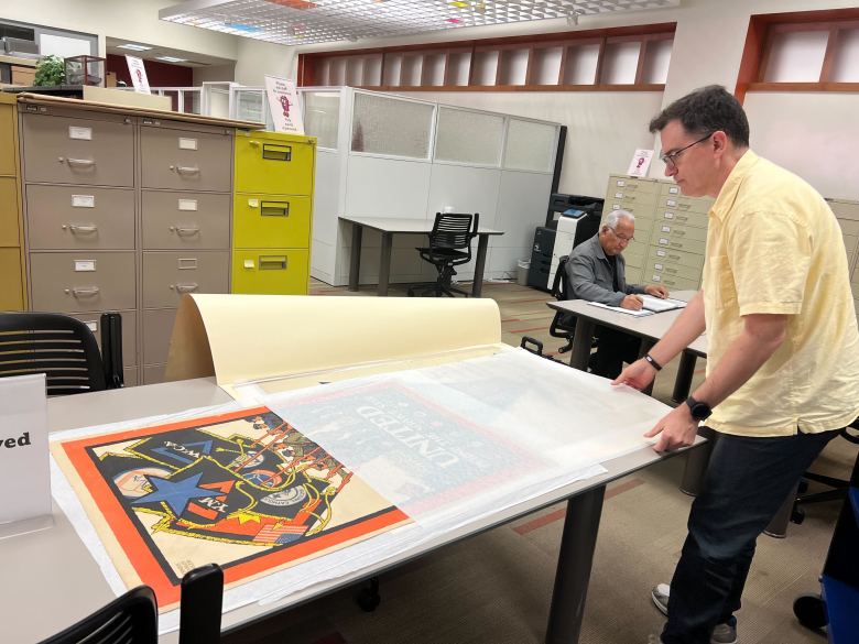 Andy Crews, Librarian 1, Special Collections shows historic posters in the Texana Research Center's collection at the Central Library downtown.