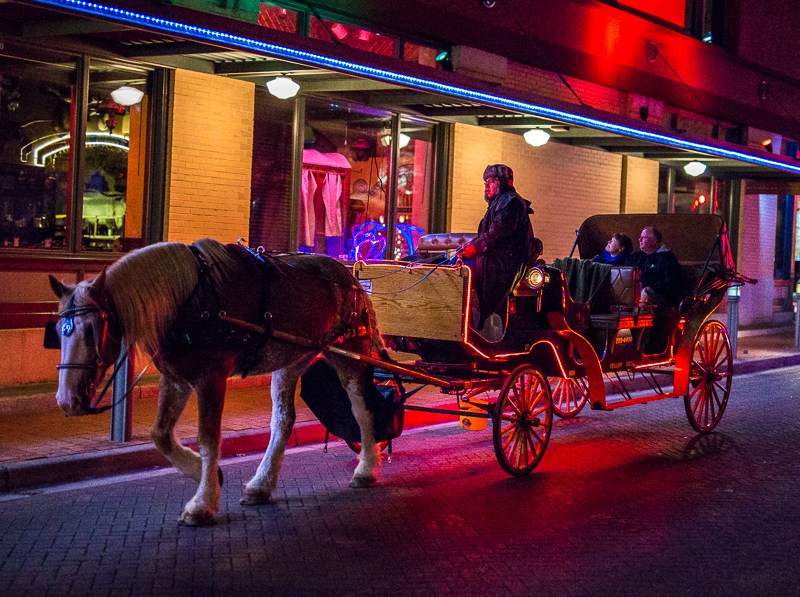 A driver leads his horse and carriage filled with passengers in downtown San Antonio. Photo by Scott Ball.