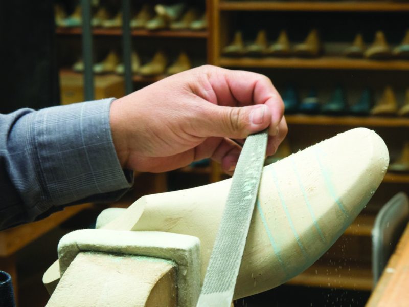 A shoe last is hand carved by a SAS employee.