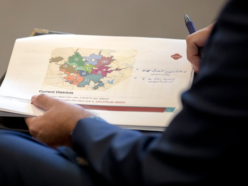 An outside attorney holds a City Council district map during a City Council meeting about redistricting in 2021.