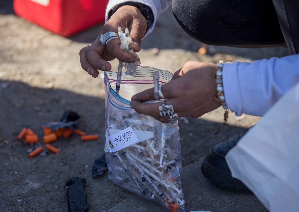 A woman collects used syringes during a weekly outreach mission performed by the Corazon Harm Reduction Center on Thursday.