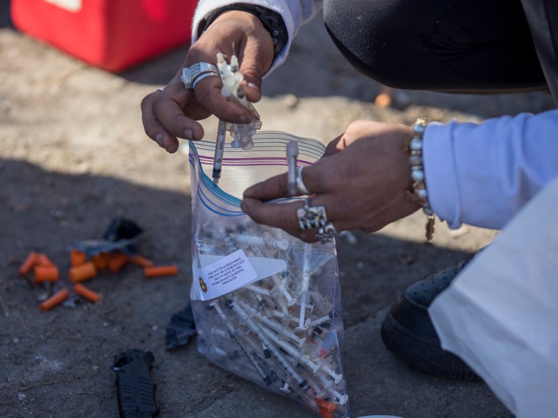 A woman collects used syringes during a weekly outreach mission performed by the Corazon Harm Reduction Center on Thursday.