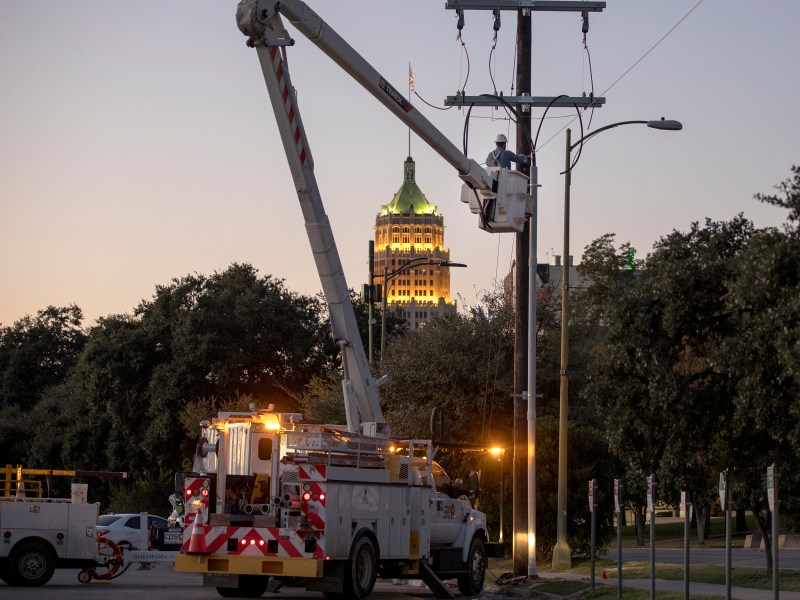 A CPS Energy lineman works on a power line downtown in November.