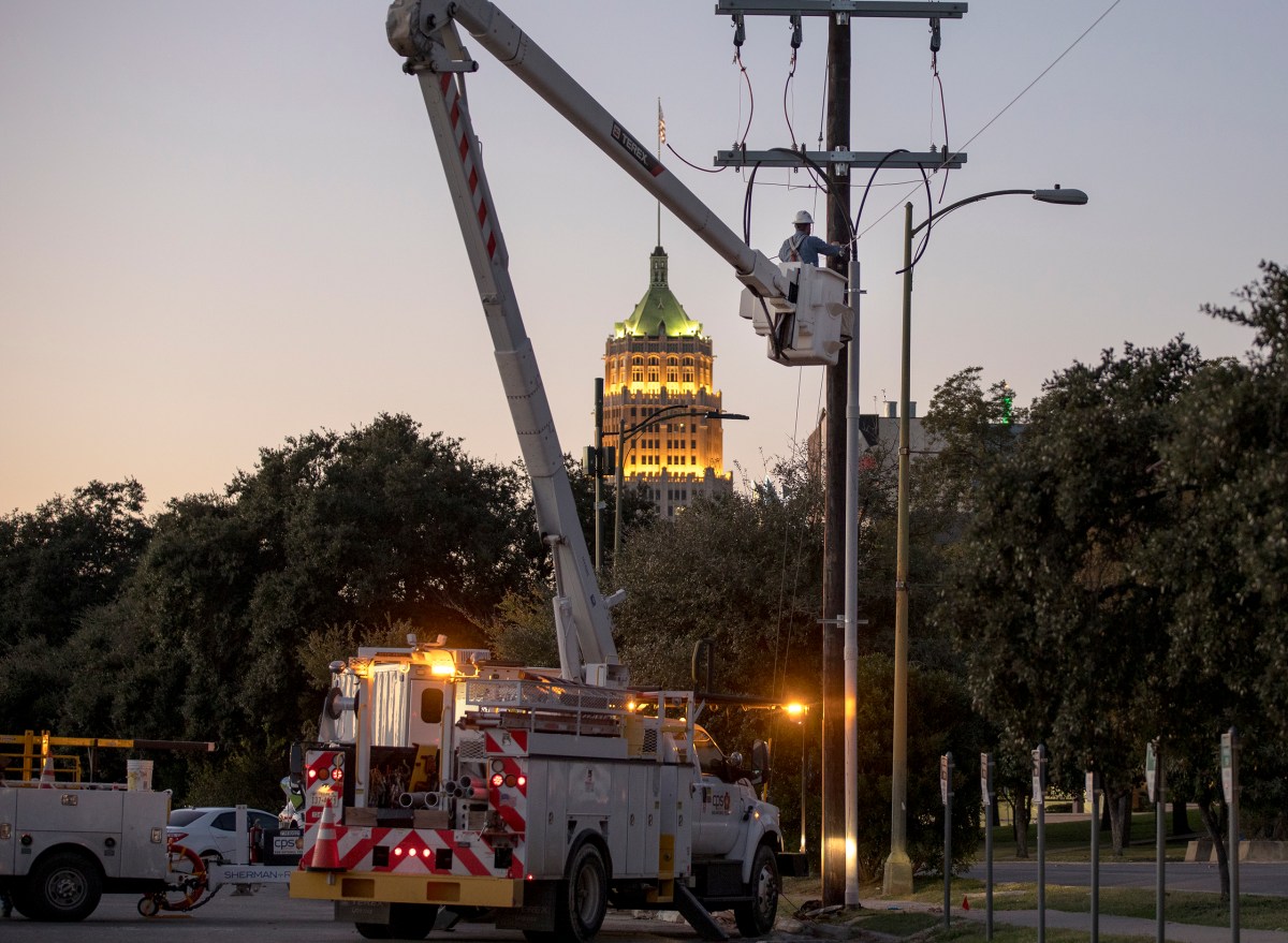 A CPS Energy lineman works on a power line downtown in November.