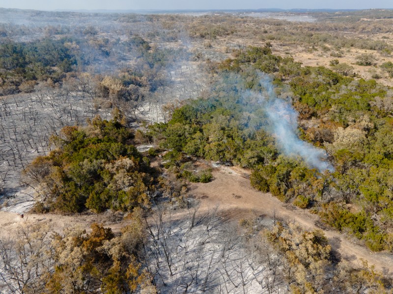 A hot spot from the Das Goat fire emits smoke in Medina County on Tuesday.