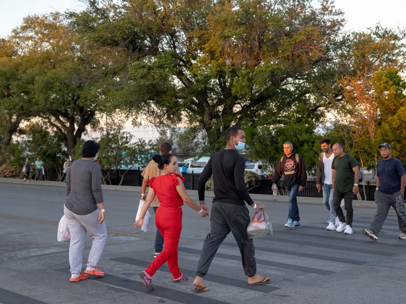 Migrants cross San Pedro Avenue outside of the migrant resource center on Saturday.