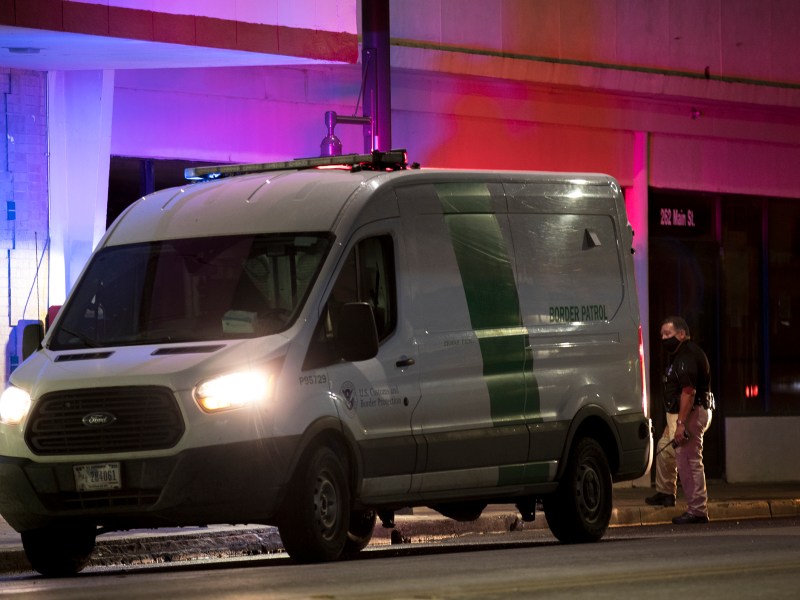 A Border Patrol prisoner transport van’s emergency lights illuminate downtown buildings in Eagle Pass on Wednesday.