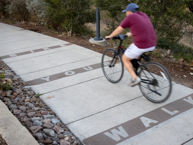 A bicyclist ignores signage instructing people to dismount and walk their bikes for a stretch of pathway along the San Antonio River on Thursday.