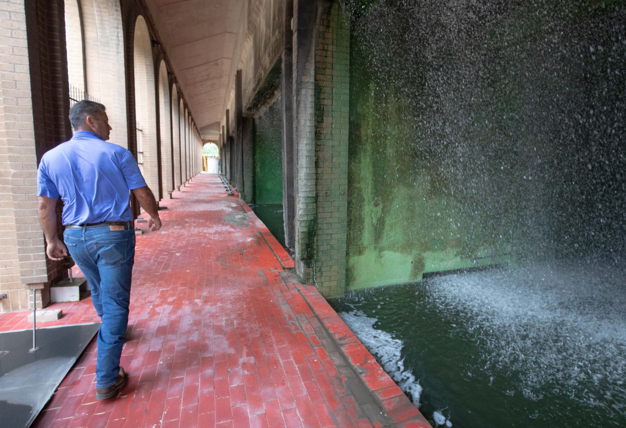 Elroy Bishop walks by the cooling towers that shower recycled water down large columns at the Cooling Plant in San Antonio.