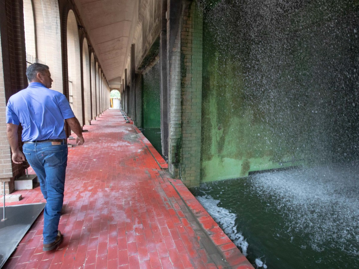 Elroy Bishop walks by the cooling towers that shower recycled water down large columns at the Cooling Plant in San Antonio.