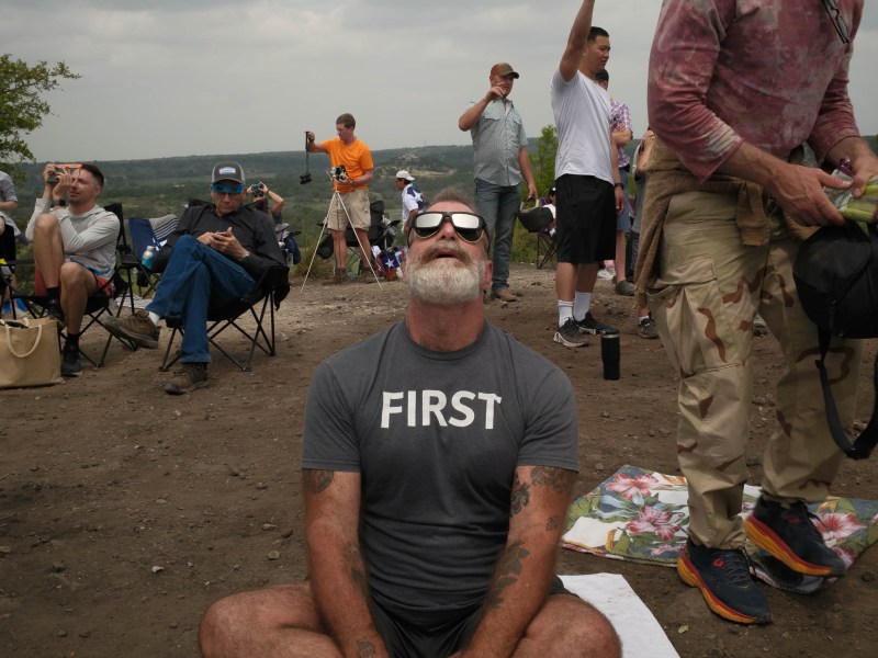 Robert John sits on top of Cross Mountain in Fredericksburg, TX for the total eclipse on Monday.