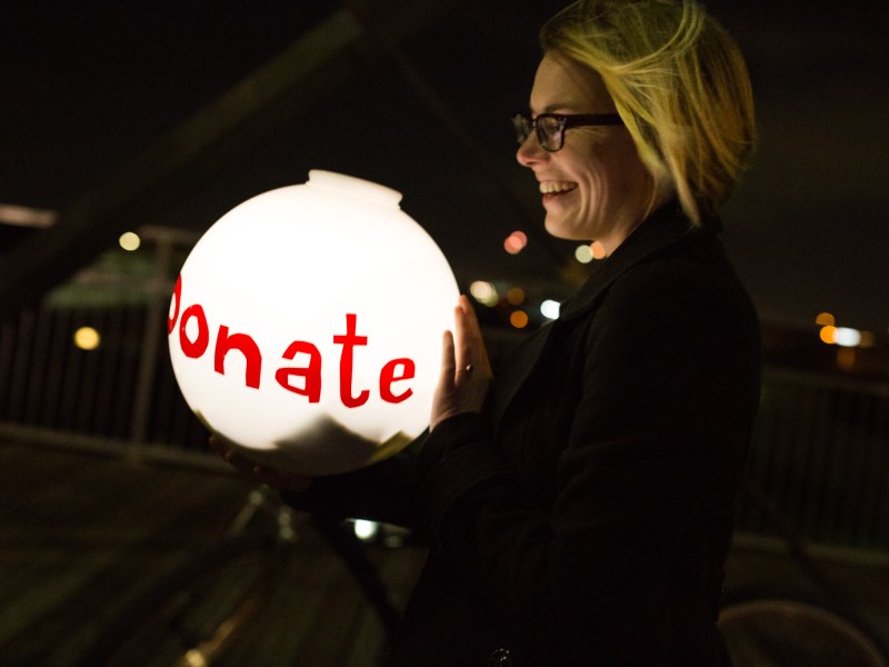 Luminaria volunteer Alyssa Danna walks with a lit globe asking for donations. Photo by Scott Ball.