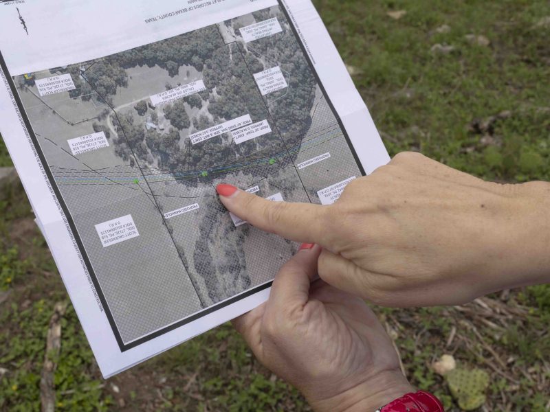 Landowner Brenda Chapman flips through pages of documents outlining the SAWS sewage line that is currently planned to run through her property which is under a conservation easement through a program with the City of San Antonio to maintain sensitive aquifer recharge zones.