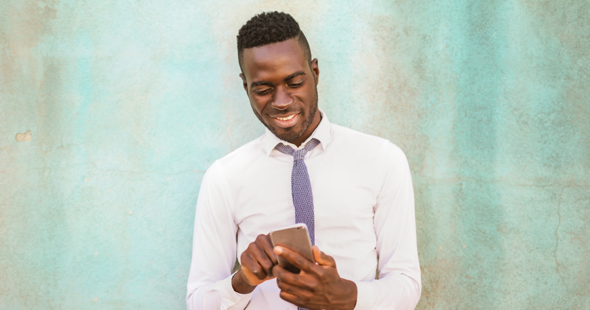 Person wearing suit smiles at cellphone