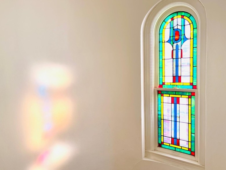 An original stained-glass window reflects colorful light throughout the stairwell in the Parker's Monte Vista home.